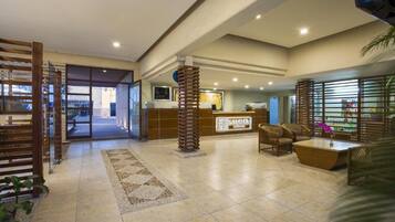Un hall de hotel con mostrador de recepción, zona de estar y un ventanal grande.