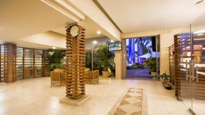 A hotel lobby with a central wooden pillar, seating area, and a view of the outdoor area. - Gamma Cuernavaca Puerta Paraiso (Cuernavaca)