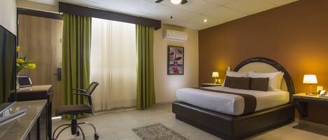 A hotel room with a bed, desk, chair, and a ceiling fan.