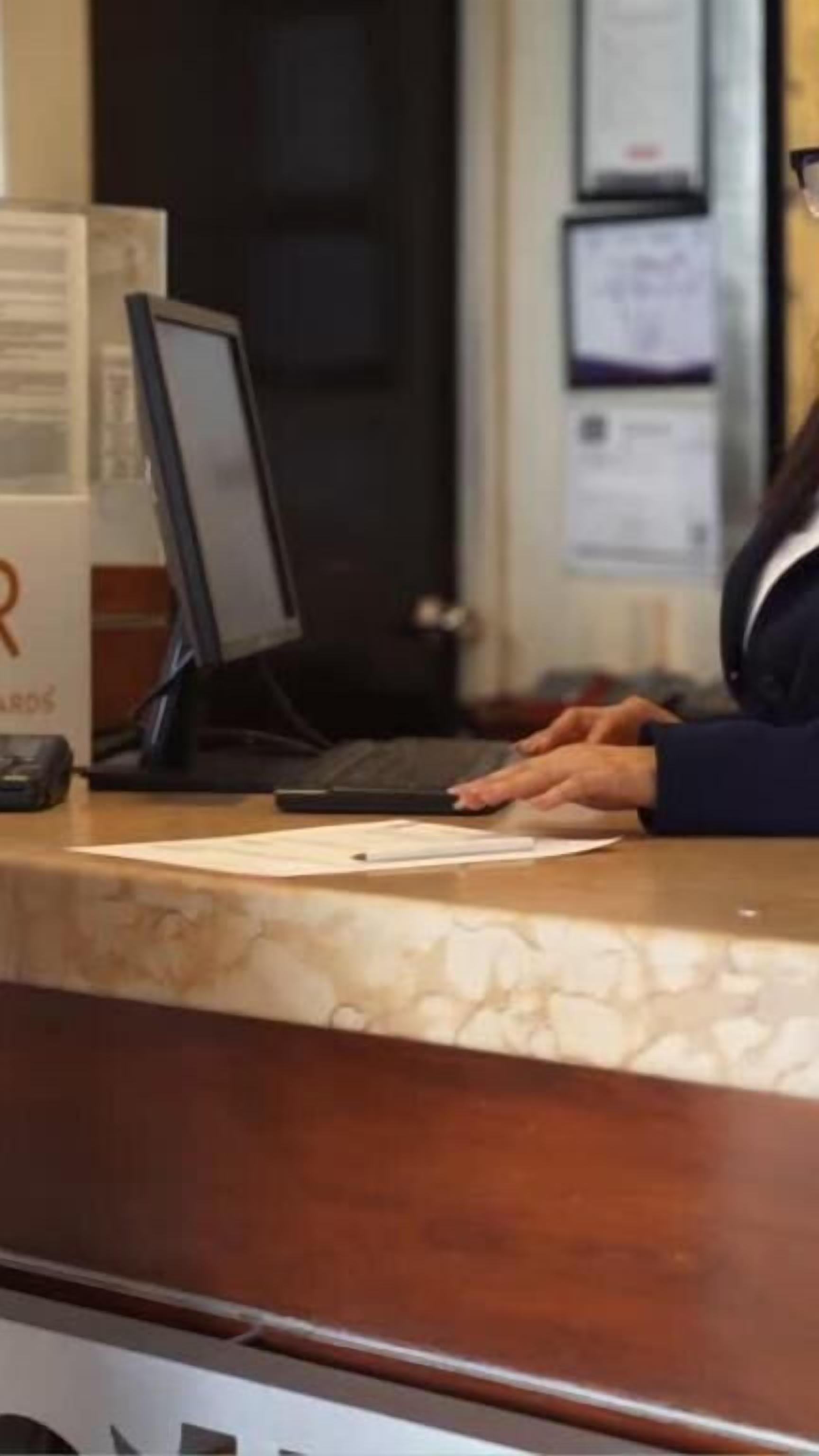 A reception desk with a laptop, a telephone, and a notepad.