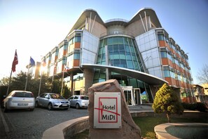 A modern hotel building with a curved facade, multiple flags, and a sign indicating it is the MiDi Hotel. - Ankara Hotel Midi (Ankara)