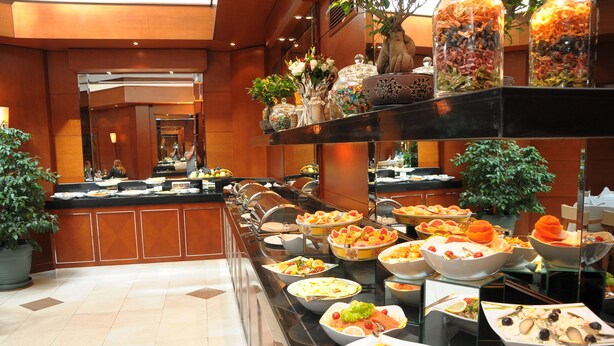 A buffet with various dishes and a large potted plant. - Ankara Hotel Midi (Ankara)