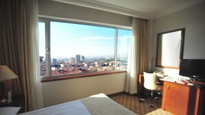 A hotel room with a large window, a bed, a desk, and a television. - Ankara Hotel Midi (Ankara)