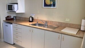 A compact kitchen with a microwave, sink, and a painting on the wall. - Motel on York (Dunedin)