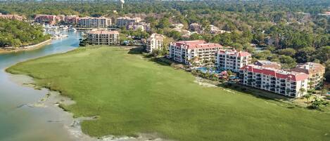 A resort with multiple buildings, a marina, and a large grassy area.