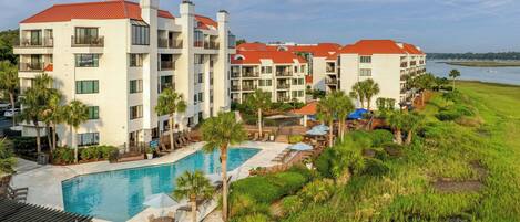 A hotel with multiple floors, a swimming pool, and a view of the water.