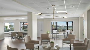 A spacious room with a large dining table, several chairs, a central coffee table, and a view of the outdoors.
