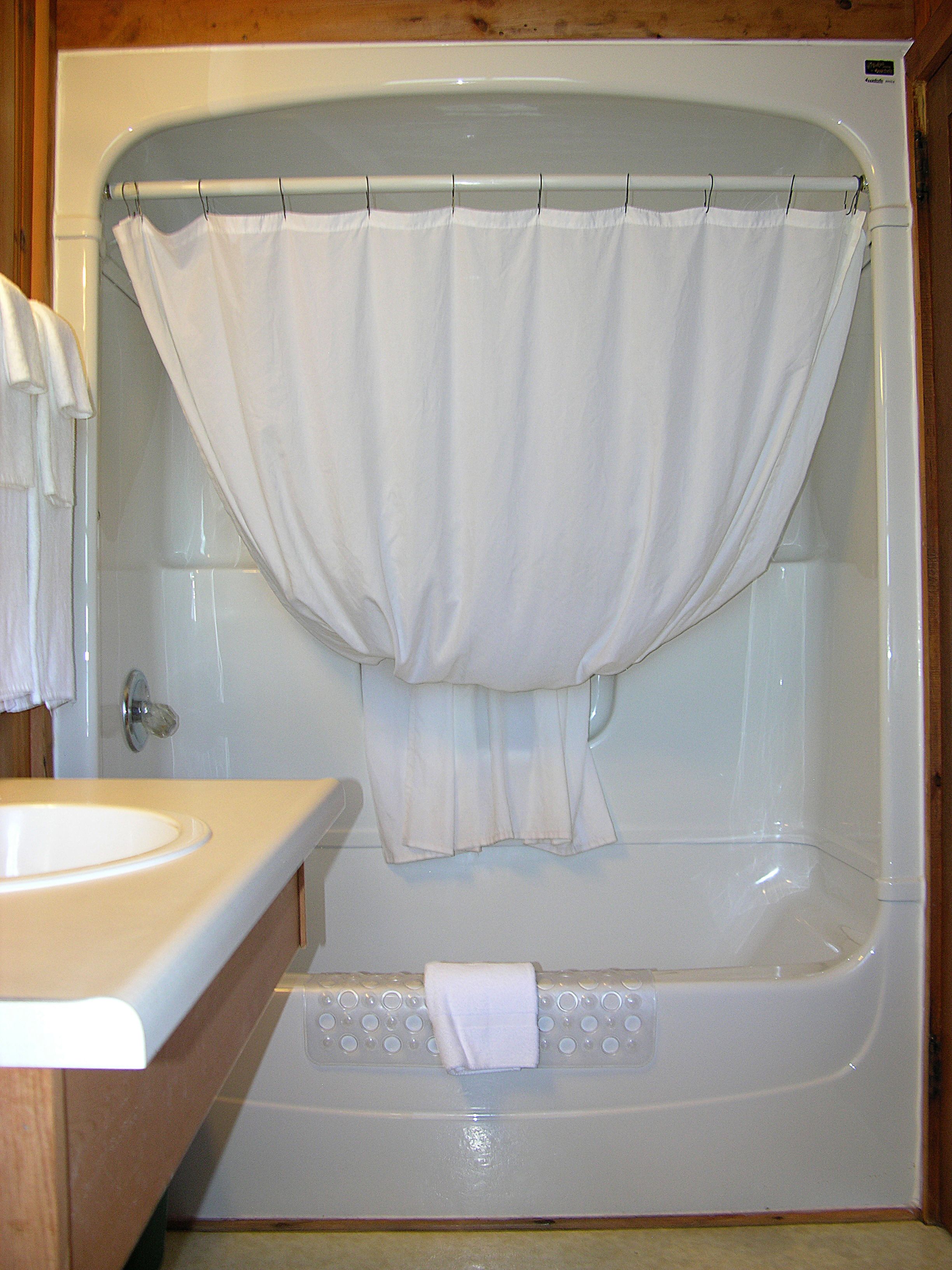 Un baño con bañera, lavamanos y tocador de madera.