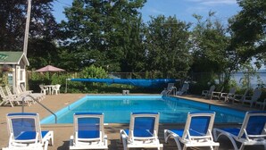 Zona de piscina con sillas de descanso y un pequeño edificio.