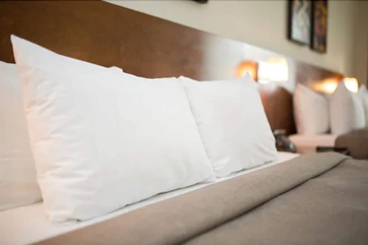 Ein Bett mit weißen Kissen und einem Holz-Kopfteil.
