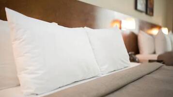 A bed with white pillows and a wooden headboard.