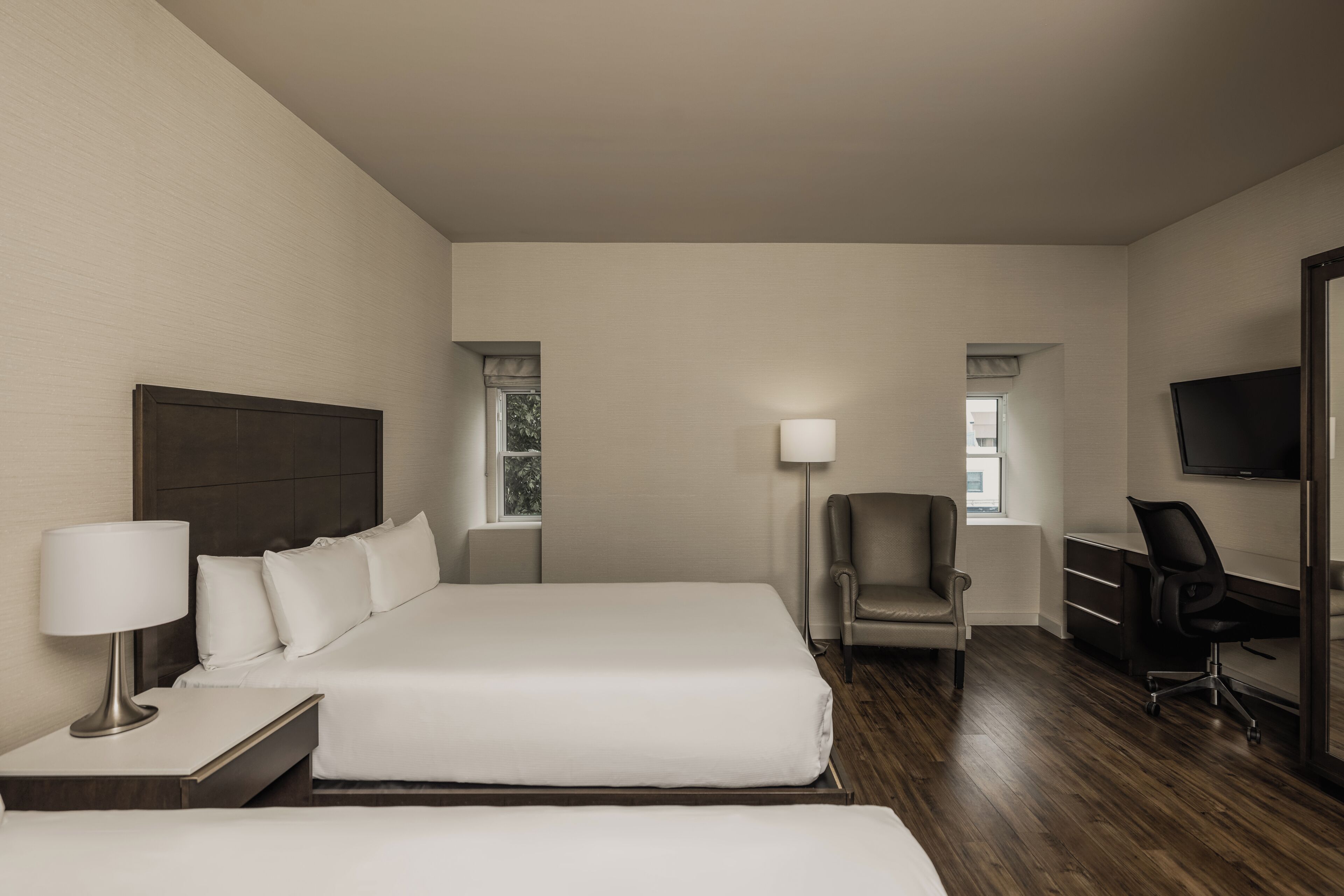 Una habitación de hotel con una cama grande, un escritorio, una silla y un televisor.