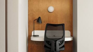 A corner office with a desk, chair, lamp, and a wall-mounted light fixture.