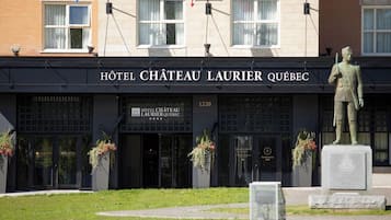 L’extérieur de l’HÔTEL CHÂTEAU LAURIER QUÉBEC se distingue par sa façade classique, ses grandes fenêtres et une statue qui se trouve devant l’entrée.