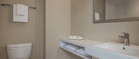 A bathroom with a toilet, sink, mirror, towel rack, and shelf with towels.