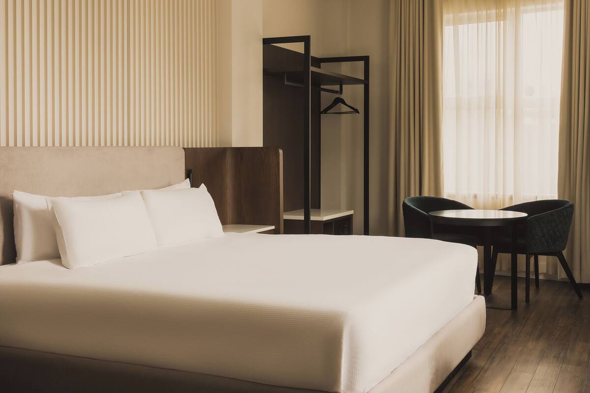 Ein Hotelzimmer mit einem großen Bett, einem Schreibtisch, einem Stuhl und einem Kleiderschrank.