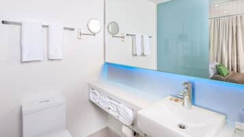 Un baño moderno con un lavabo blanco, un espejo grande y dos toallas colgadas en un perchero.