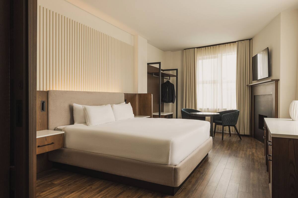 Ein Hotelzimmer mit einem großen Bett, einem Schreibtisch, einem Stuhl, einem Fernseher und einem Kleiderschrank.