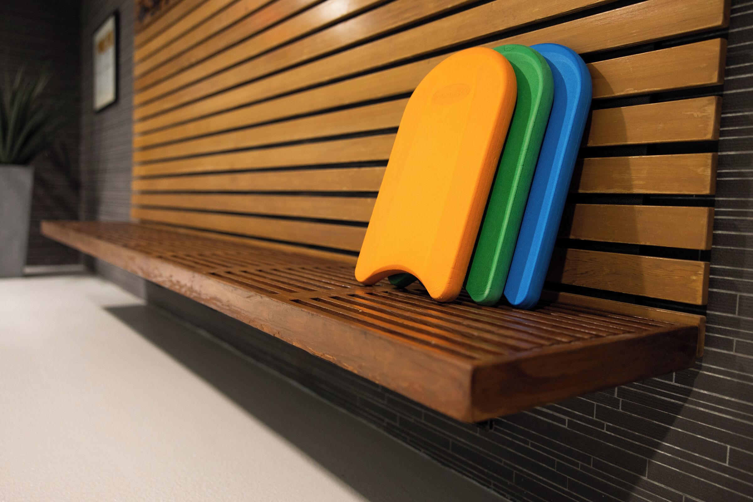 A wooden bench with three colorful objects placed on it.