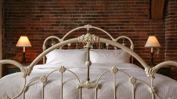 A bed with a white metal frame and a brick wall background.