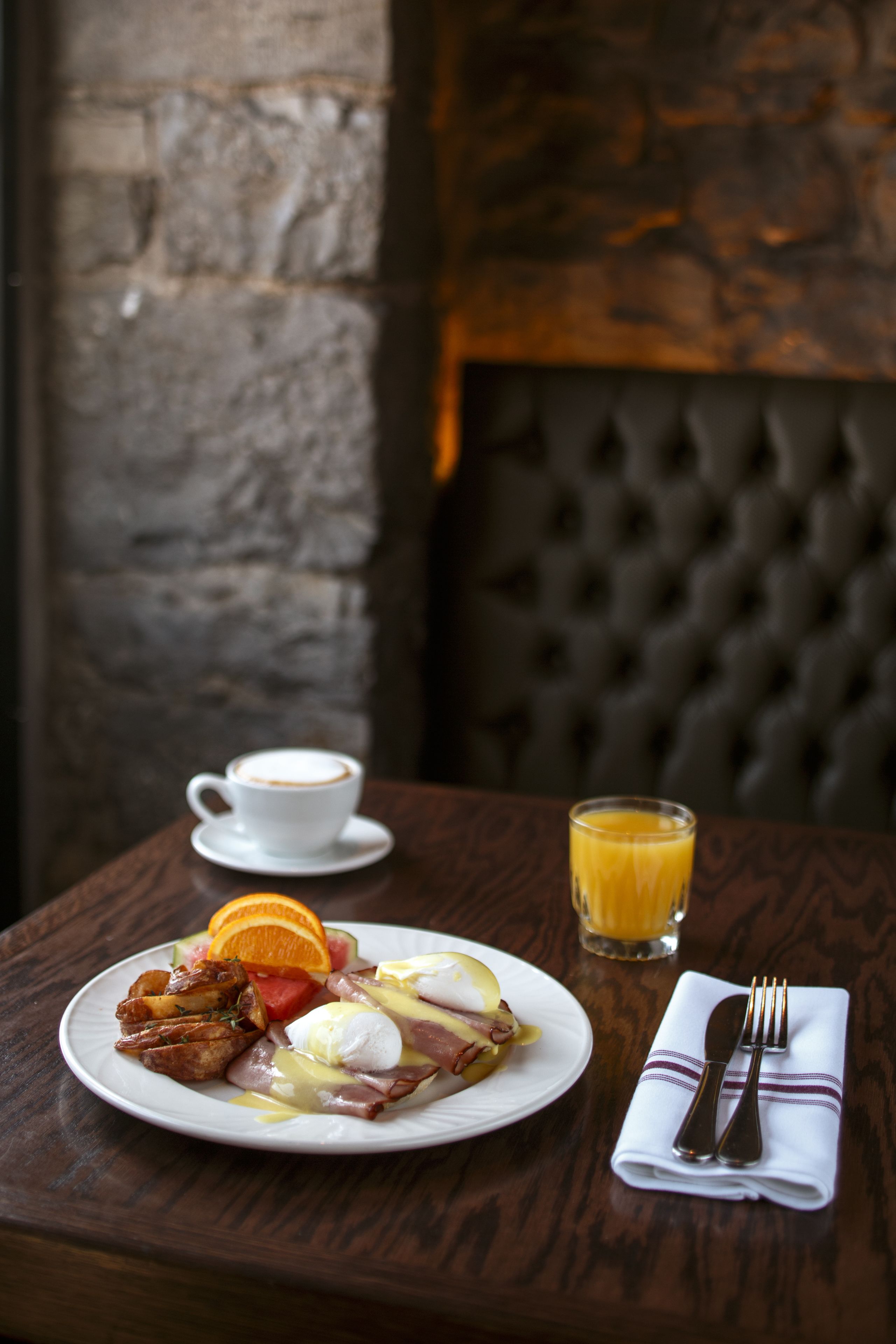 A breakfast setting with a plate of food, a cup of coffee, and a glass of orange juice on a wooden table.