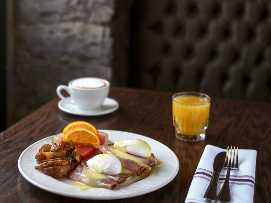 A breakfast setting with a plate of food, a cup of coffee, and a glass of orange juice on a wooden table.