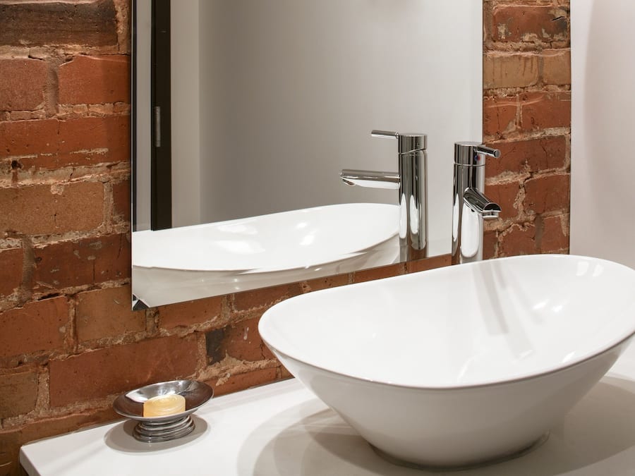 Une salle de bain avec un lavabo blanc, un robinet chromé et un grand miroir.