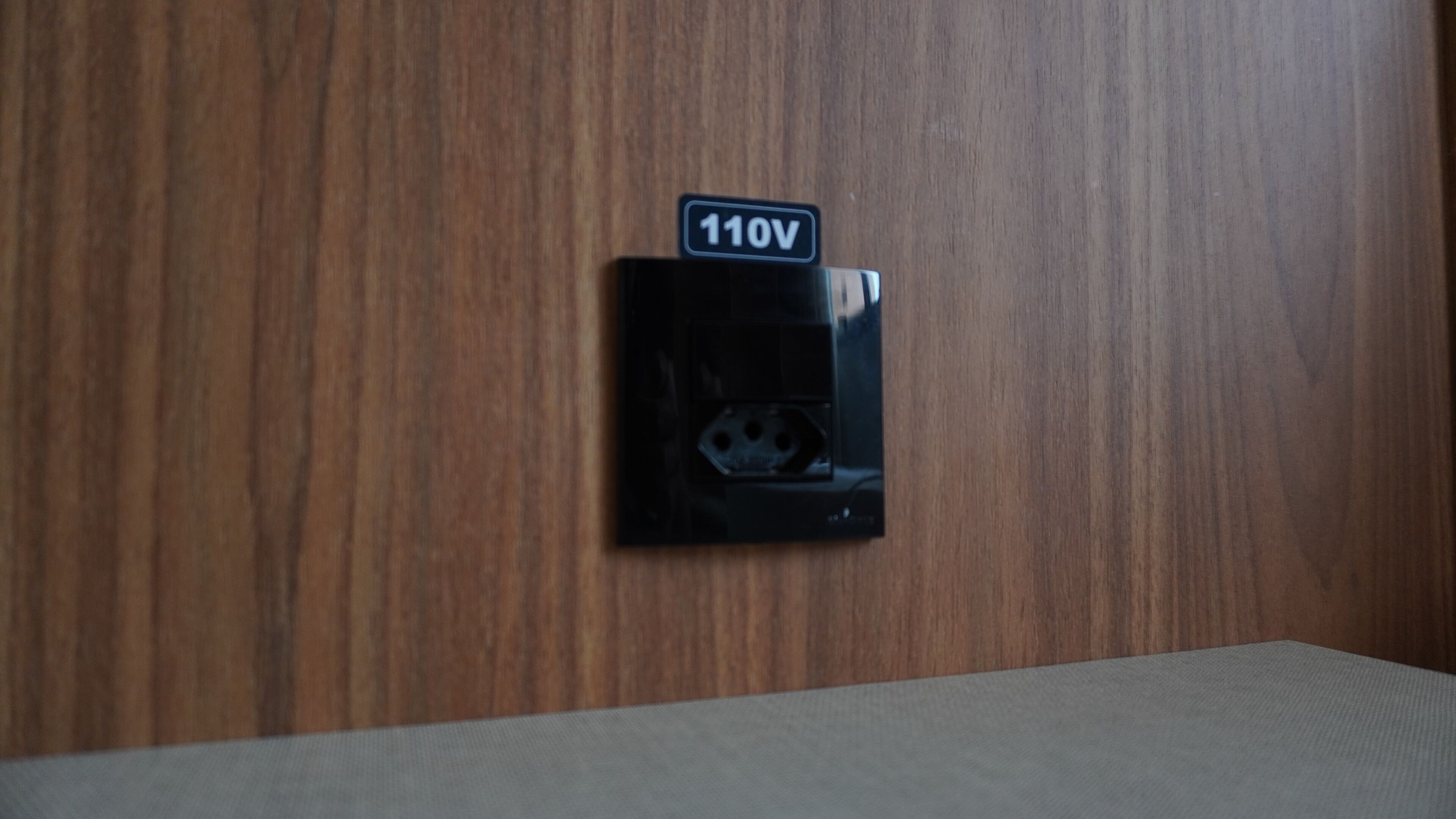 A wall-mounted electrical outlet with a 110V sign.