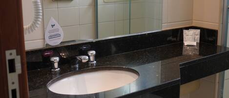A bathroom with a sink, mirror, and towel rack.