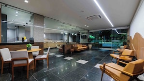 A modern lobby with a dining area, seating, and a view of the outdoors. - Vitória Praia (Vitoria)