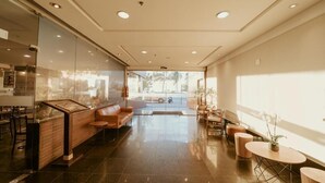 A modern hotel lobby with a reception desk, seating area, and large windows providing natural light. - Vitória Praia (Vitoria)