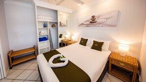 A neatly arranged hotel room with a bed, a bedside lamp, a small table, and a wardrobe.