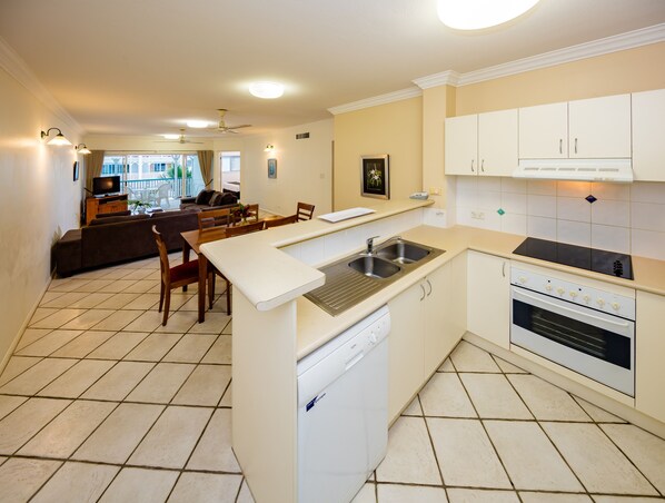 A compact kitchen with a dishwasher, a sink, and a stove. There is a dining area with a table and chairs.