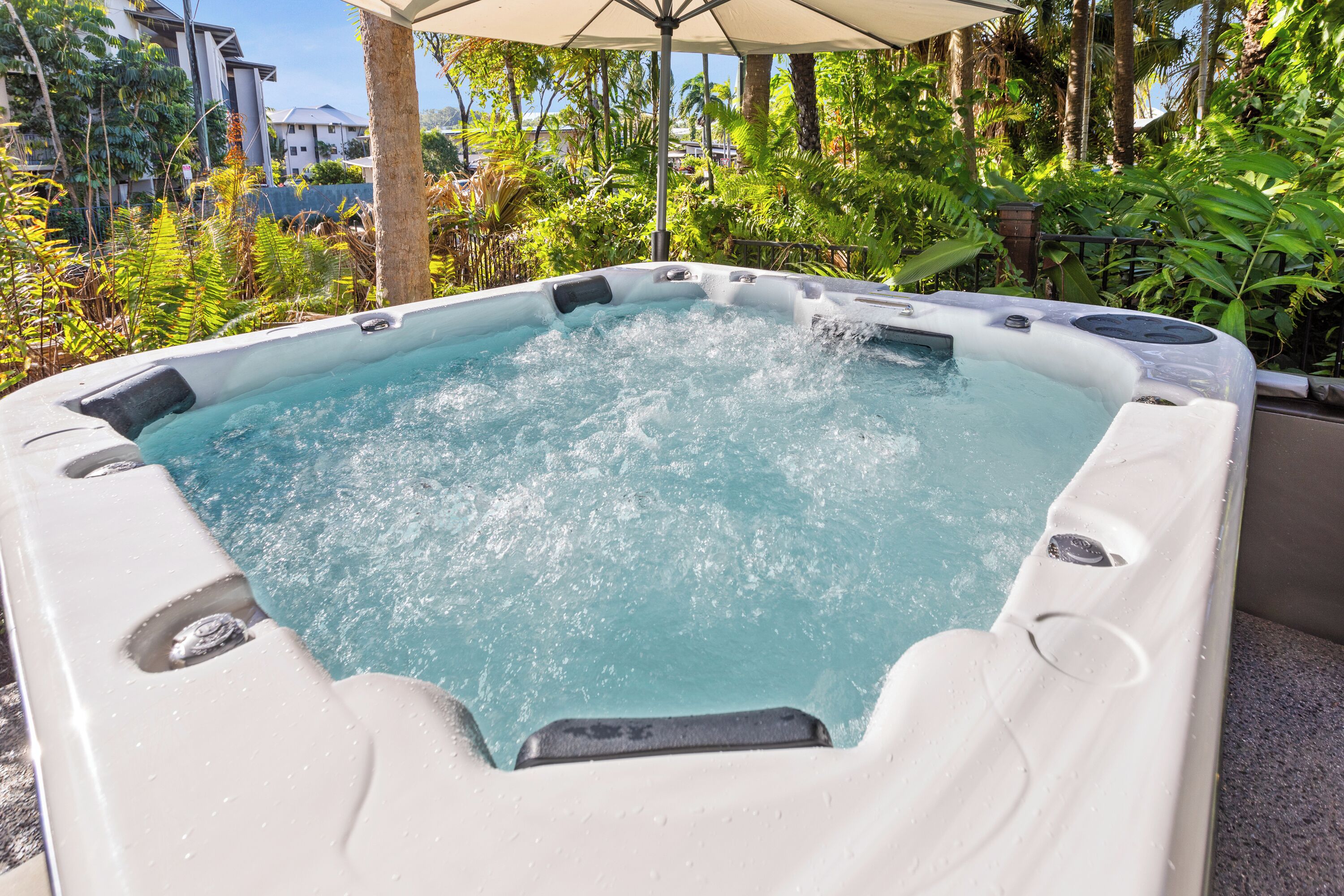 A hot tub surrounded by lush greenery and a clear sky.