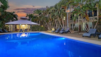 Una piscina al aire libre, sillones reclinables de piscina