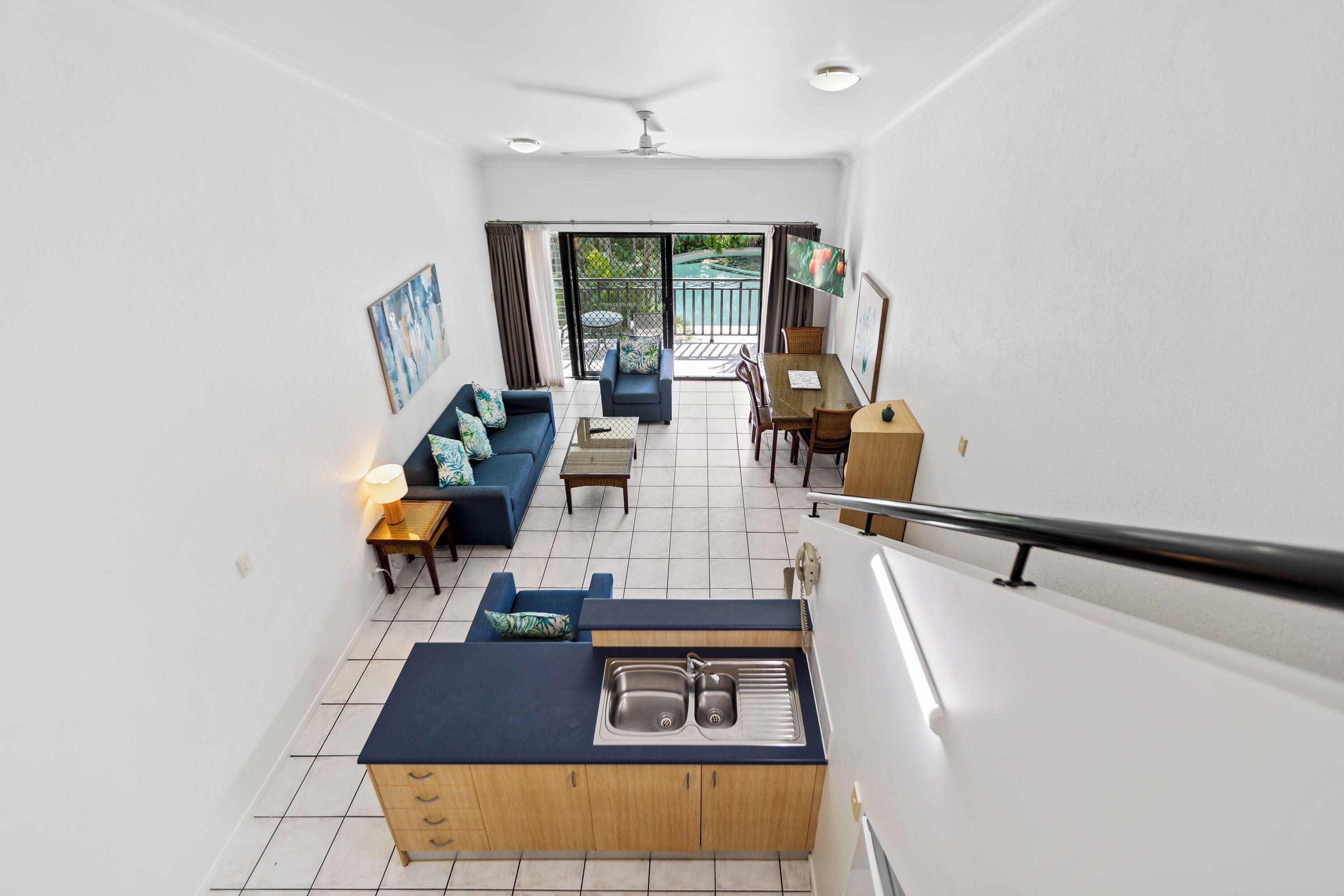A modern interior with a kitchen, dining area, and a balcony with a pool view.