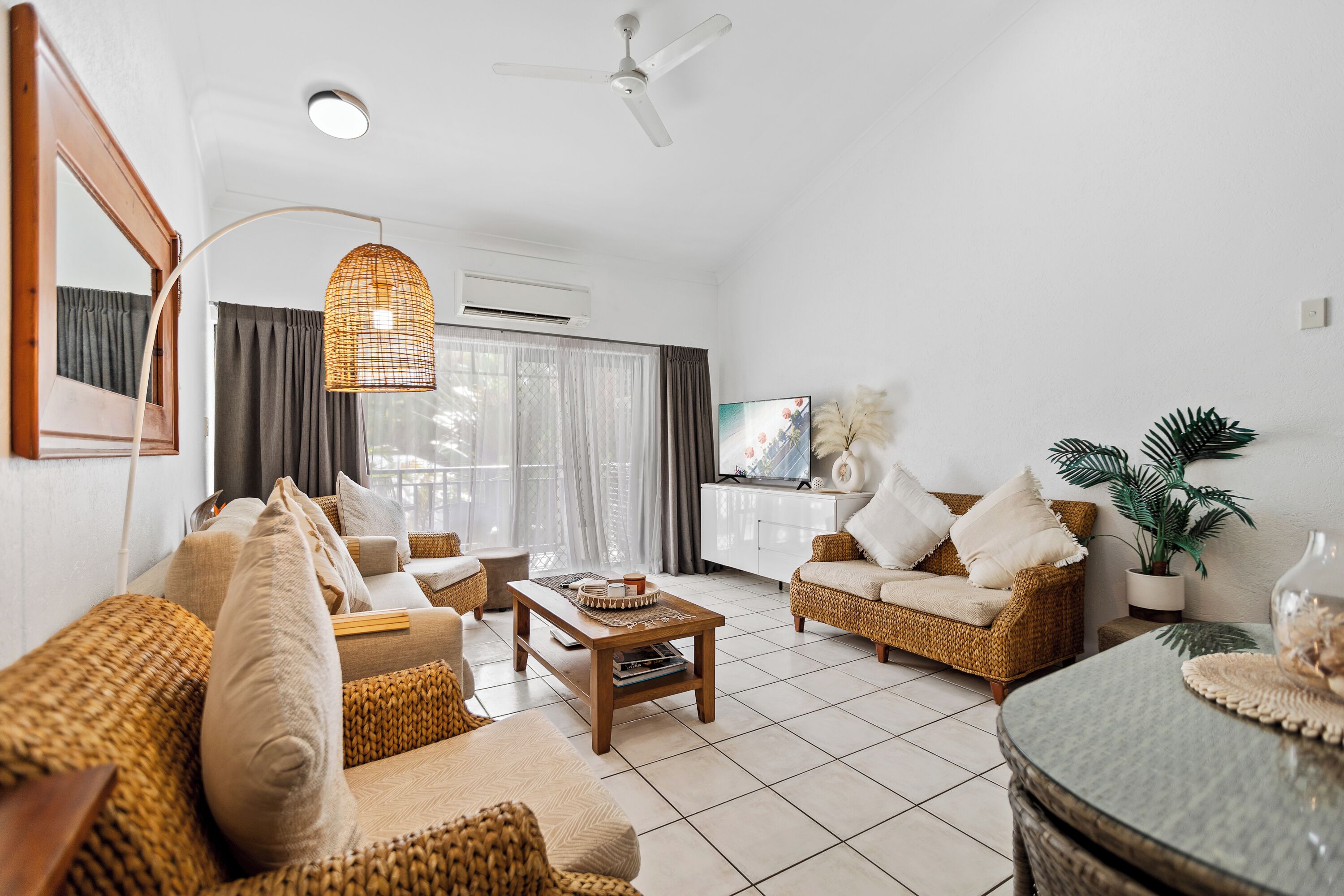 A living room with wicker furniture, a wooden coffee table, and a ceiling fan.