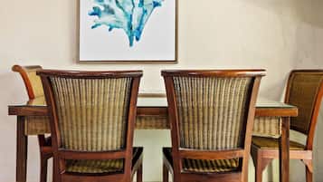 A dining area with a table and chairs, a framed artwork, and a television on the wall.