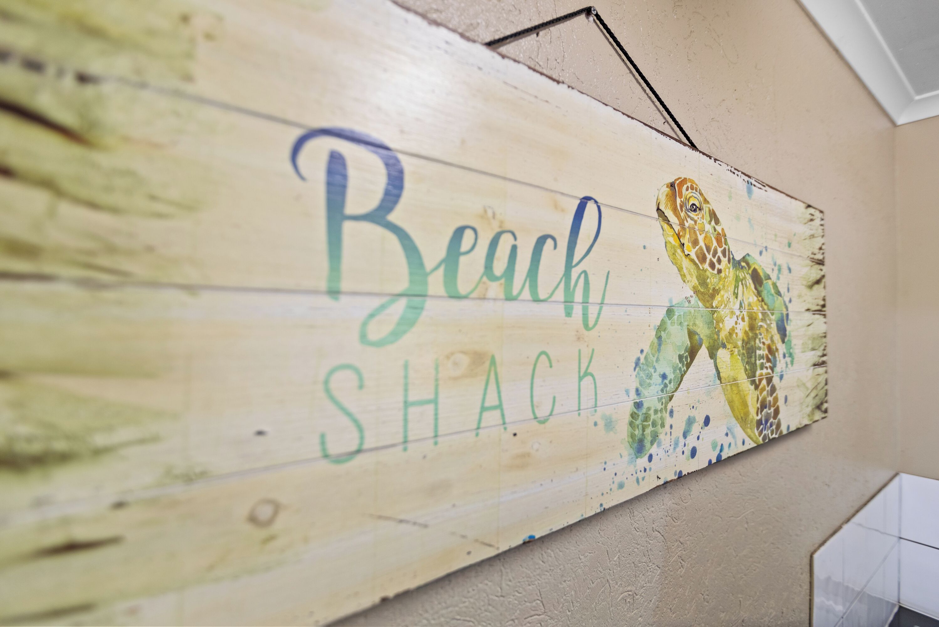 Ein Holzschild mit der Aufschrift 'Beach Shack' und einer Schildkröten-Illustration.