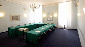 Un salón de conferencias con una larga mesa, sillas, un proyector y una araña.