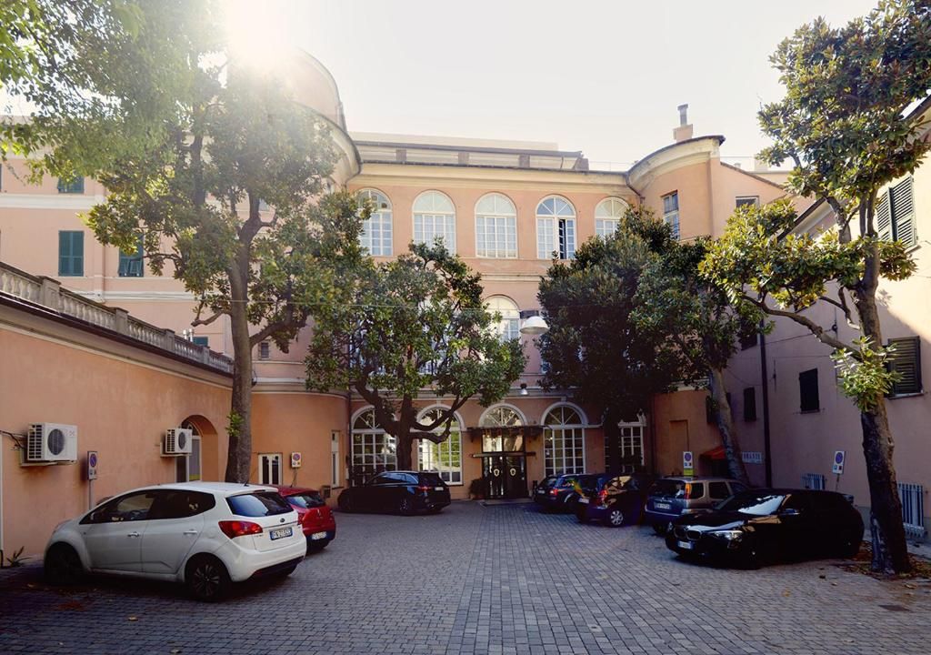 A courtyard with parked cars, trees, and a building with arched windows.