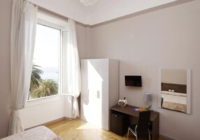 Een hotelkamer met een bed, een bureau met stoel, een televisie en een raam met gordijnen.