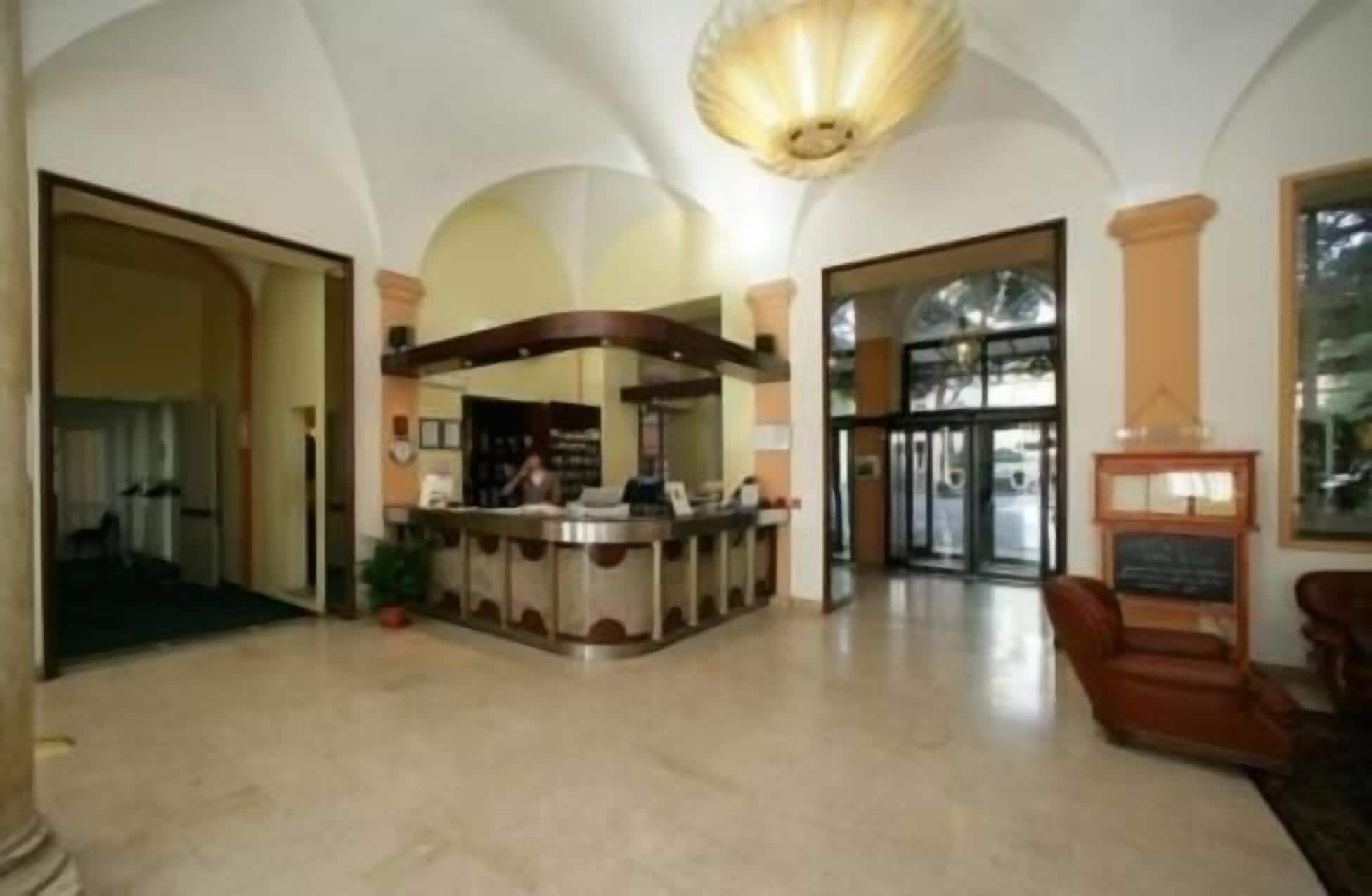 A lobby with a reception desk, a fireplace, and a large arched doorway.