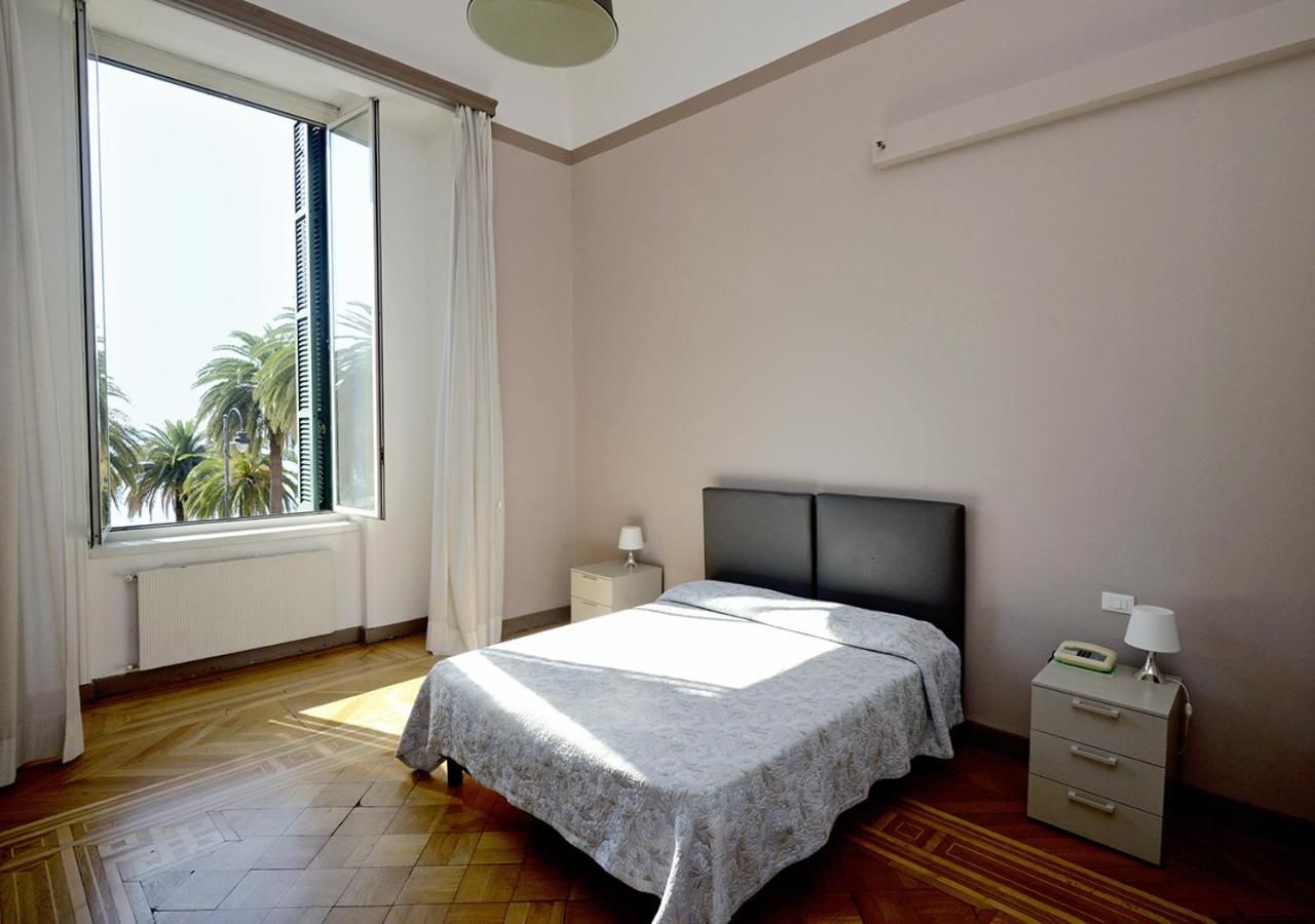 Een slaapkamer met een bed, nachtkastjes, een raam met gordijnen en een radiator.