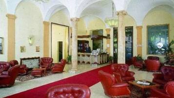 A lobby with red leather chairs, a red carpet, and a chandelier.