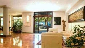 Un vestíbulo de hotel con una recepción, un área de descanso y vistas al exterior.