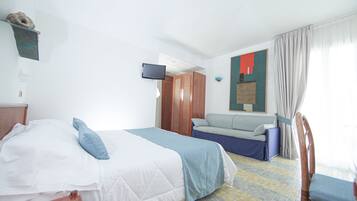 Una habitación de hotel con cama, sofá, televisión y una silla.