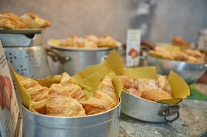 Un buffet con diversi prodotti da forno in contenitori metallici.
