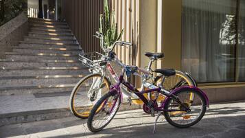 Una bicicleta estacionada en una escalera de piedra que lleva a un edificio con paneles de madera verticales y un ventanal grande.