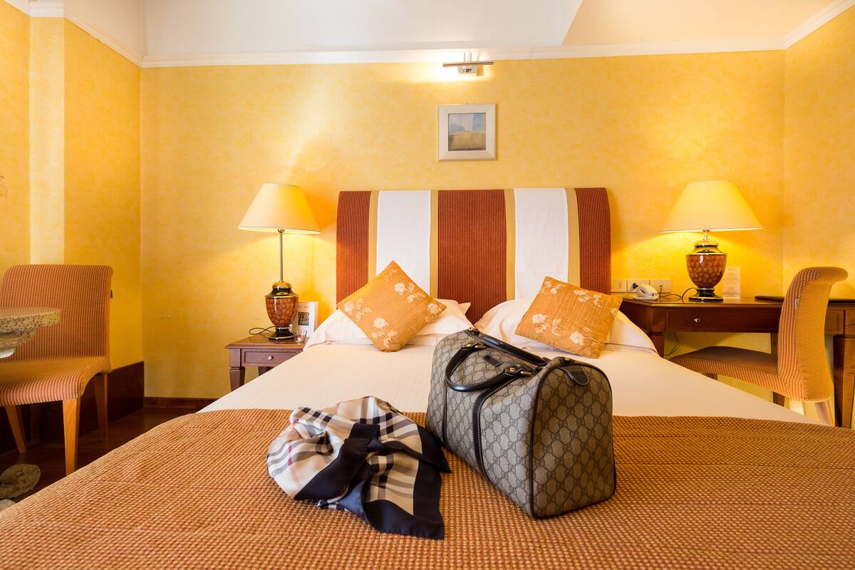 Una habitación de hotel con una cama, dos sillas, un escritorio y una l ámpara.